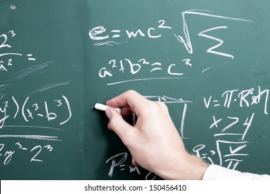 A Hand Writing Math Equations Upon A Chalkboard