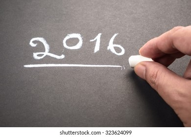 Hand writing numbers of year 2016 on chalkboard