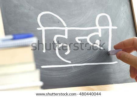 Hand writing on a blackboard in a language class with the text 