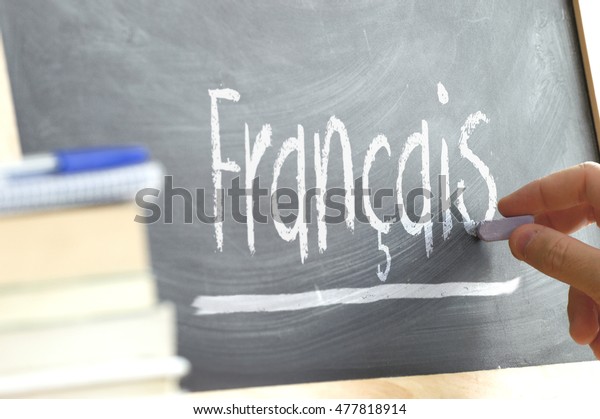 Hand writing on a blackboard in a language\
class with the word \
