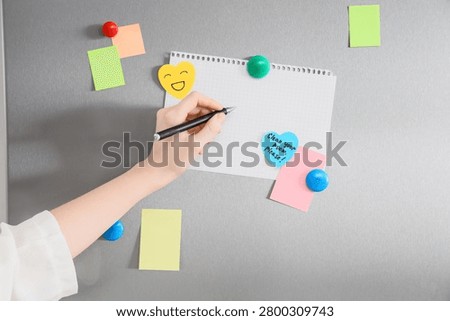 Hand writing on blank notepad with magnets and sticky notes on refrigerator door, home organization and communication, home organization and family communication are essential for daily life