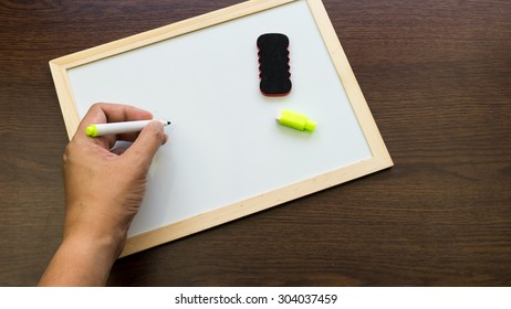 Hand writing on empty white boards on wooden surface. Concept of school or business message. Slightly de-focused and close-up shot. Copy space.