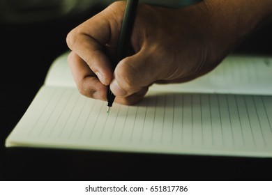 a hand writing on a notebook