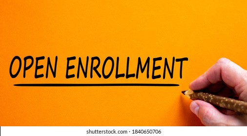 Hand writing 'open enrollment', isolated on beautiful orange background. Concept. Copy space.