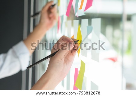 Hand writing paper note, sticky note on glass window with close up shot.