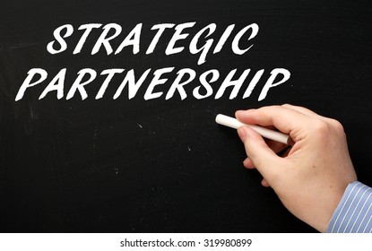 Hand Writing The Phrase Strategic Partnership In White Text On A Blackboard. Companies  And People Enter Into Strategic Partnerships To Develop Business And Leverage Opportunities