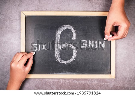 Hand writing from the point of view of 6 and 9 number on chalkboard in opposite direction, argument in different perspectives concept