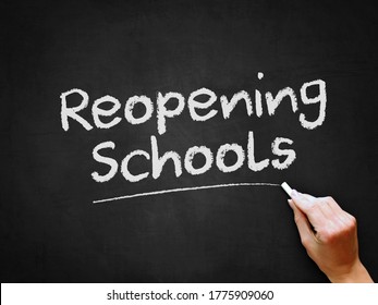 A Hand Writing 'Reopening Schools' On Chalk Board For Schools Reopening Plans After Covid-19 (Coronavirus) Pandemic Lockdown.