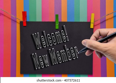 Hand Writing Welcome! New Member On Black Envelope Hanging By A Rope Against Multiple Color Background.