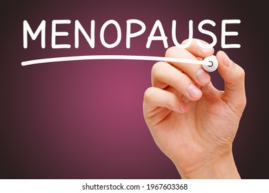 Hand writing the word Menopause with white marker on dark pink background. Concept about Menopause transition into a new phase of life when the menstrual cycle finishes.