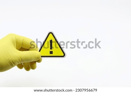 Hand with yellow glove and the alert or caution symbol. Space for text.