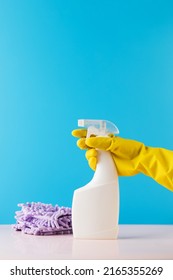 A Hand In A Yellow Glove Holds A Spray Bottle Mockup With Detergent On A Blue. Cleaning, Cleaning Service. Copy Space.