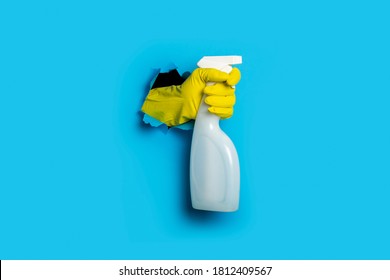 Hand in yellow gloves holding spray on a bright blue background - Shutterstock ID 1812409567