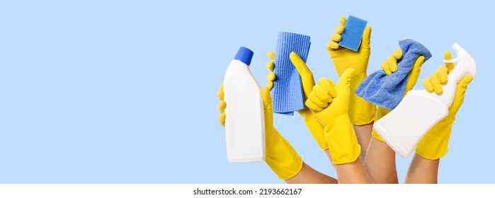 hand with yellow rubber glove holding cleaning supplies on blue background. banner with copy space - Powered by Shutterstock