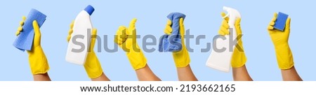 hand with yellow rubber glove holding cleaning supplies isolated on blue background. banner