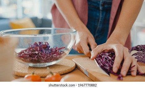 Hand of young Asian woman chef hold knife cutting Red Chinese cabbage on wooden board on kitchen table in house. Cooking vegetable salad, Lifestyle healthy food eating and traditional natural concept. - Powered by Shutterstock