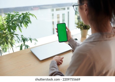 Hand Of Young Businesswoman Holding Smartphone With Blank Green Screen