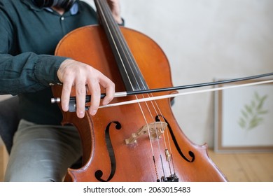 Hand Of Young Cello Player Gliding Fiddlestick Across Strings While Performing Piece Of Music In Front Of Camera