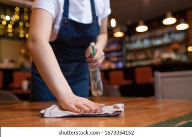 Hand of young contemporary waitress wiping wooden table with duster and detergent in the end of working day - Powered by Shutterstock