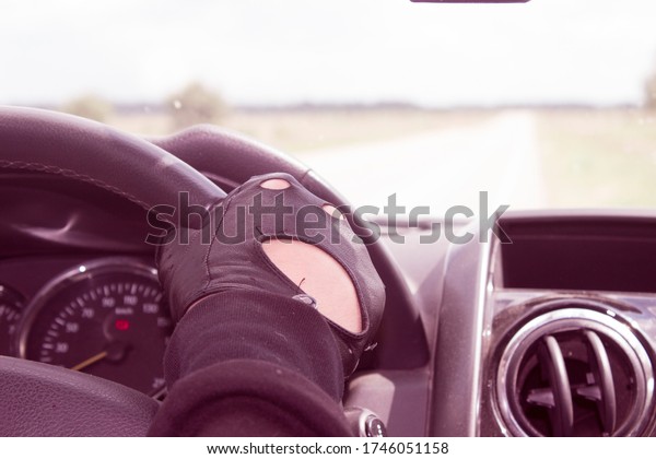 The hand of a young driver in a leather glove on\
the steering wheel of the\
car