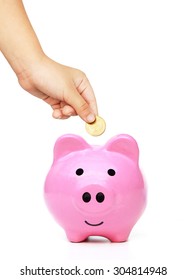 Hand Of A Young Female Child Putting A Coin Into A Pink Piggy Bank - Kid Saving Money For Future Concept