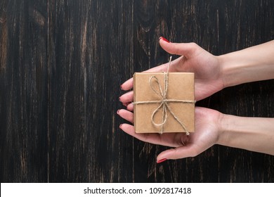 Hand Of A Young Girl Opening A Gift Box On A Dark Wooden Background.