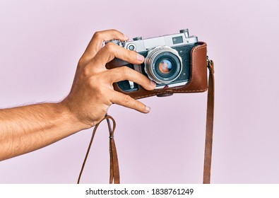 Hand of young hispanic man holding vintage camera over isolated pink background. - Powered by Shutterstock