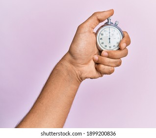 Hand of young hispanic man using stopwatch over isolated pink background. - Powered by Shutterstock