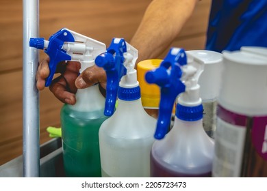 Hand Of Young Janitorial Worker Holding A Sprayer With Cleaner In Trolley Of Cleaning Supplies