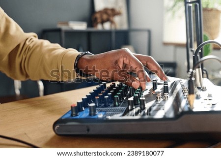 Hand of young male host turning consoles on soundboard