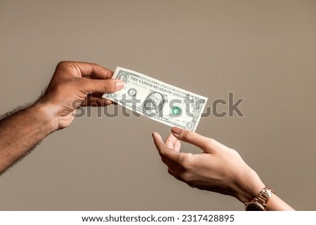 Hand of a young man giving one dollar to a women.