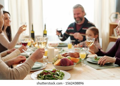 Hand of young man holding glass of wine over served table during toast at festive family dinner on Thanksgiving day - Powered by Shutterstock