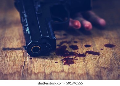 hand of young man holding gun with red blood on wooden floor, committed suicide , conceptual image