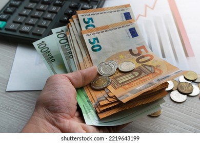 The Hand Of A Young Man Holds Banknotes On The Background Of Economic Charts. Macro Photography. Concept Of Money Market, Financial Economy.