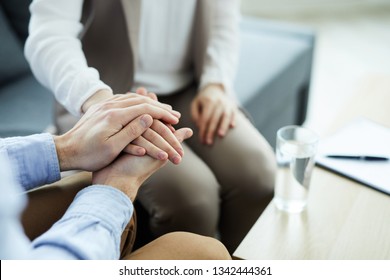 Hand of young woman between those of counselor supporting her during psychological session