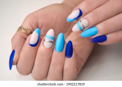 The hand of a young woman with blue gel polish and geometric design. Manicure ideas.
