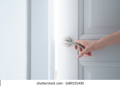 The Hand Of A Young Woman Gently Opens A Gray Classic Light Door In Art Nouveau Style From Which A Bright Light Shines. Empty Space For Text.