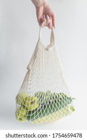 The Hand Of A Young Woman Holds A String Bag With Vegetables.