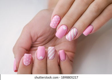 The hand of a young woman. The nails are covered with pink gel polish for Valentine's Day. Nail art and design ideas, heart.