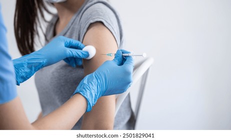 Hand of young woman nurse, doctor giving syringe vaccine, inject shot to Asian arm's patient. Vaccination, immunization or disease prevention against flu or virus pandemic concept