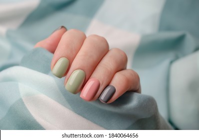 Hand of a young woman on a gray background. Gel Polish in autumn and winter colors. The idea of the manicure.