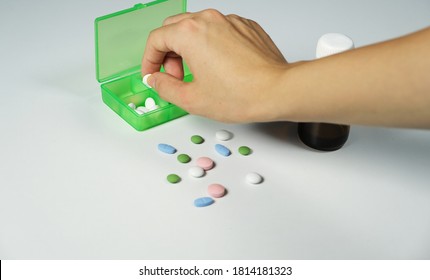 Hand Of Young Woman Taking Medicine.Pills,green Pill Box And Young Woman Hand In White Background.
Hand Taking Medicine From Green Box.