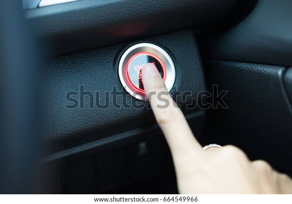 hand of young\
woman using finger for press start engine button with light and\
have leather interior detail are background. image for\
car,interior,transport and vehicle\
concept