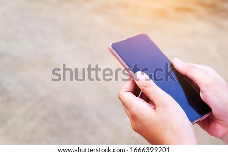 The hand of a young woman using a mobile phone with a blank screen on the aisle.