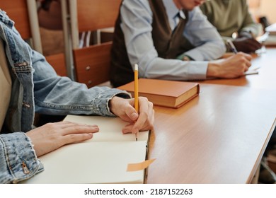 Hand Of Youthful Girl Holding Pencil Over Blank Page Of Copybook While Making Notes After Teacher Explaining New Subject At Lesson