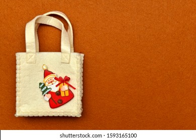  Handbag With Handles, With Decorative Wooden Figurine Of Santa Claus Sewn In The Corner, On A Red Felt Background.