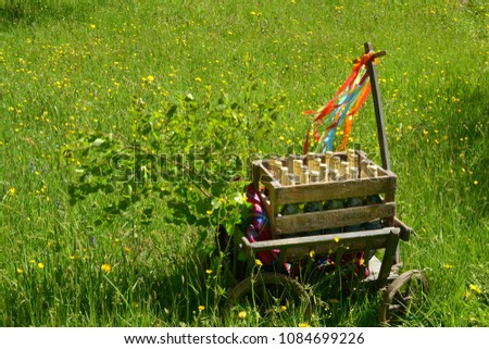A handcart with a blanket, a beer box, colorful ribbons on a wonderful spring meadow for fathers day