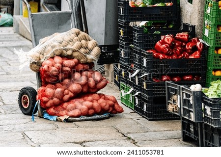 A handcart loaded with sacks of potatoes and several stacked boxes full of organic vegetables straight from the field. Outdoor fresh produce market concept with an urban setting.