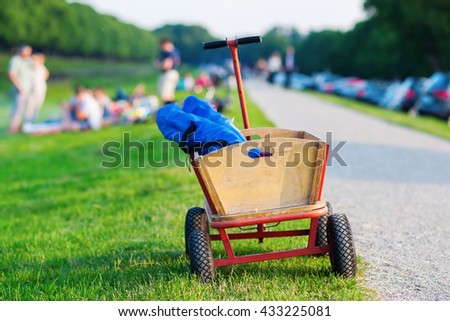 handcart for picnic standing at a meadow with people having a picnic in the blurred background