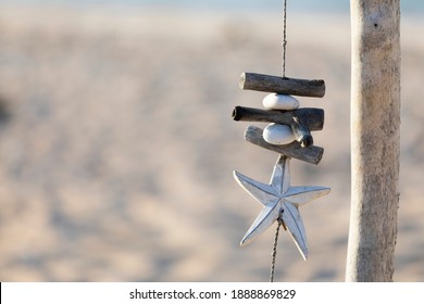 handcrafted decoration of drift wood and sea shells fluttering in the wind with a blurred back ground